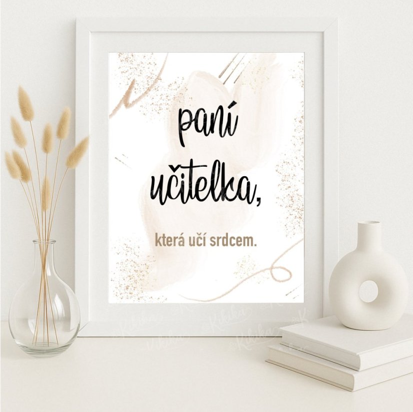 Plakát „Paní učitelka, co učí srdcem“ ve starorůžové barvě zarámovaný v rámečku, umístěný na světlém s květinovou dekorací. KIKIKA